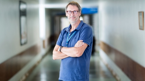Roger Barker standing in hospital corridor, arms crossed, looking to camera